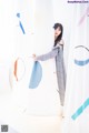 A woman standing in front of a white curtain.