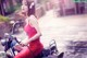 A woman in a red dress sitting on a motorcycle.