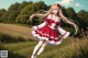 A girl in a red and white dress is walking in a field.