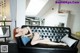 A woman laying on a black couch in a living room.