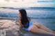 A woman in a blue bikini laying on the beach.