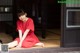 A woman in a red dress sitting on the floor.