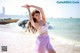 A woman in a purple skirt is dancing on the beach.