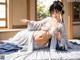 A woman in a white and blue kimono laying on a bed.