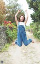 A woman jumping in the air on a dirt road.