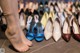 A woman standing in front of a row of pairs of shoes.