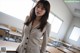 A woman standing in front of a classroom full of desks.